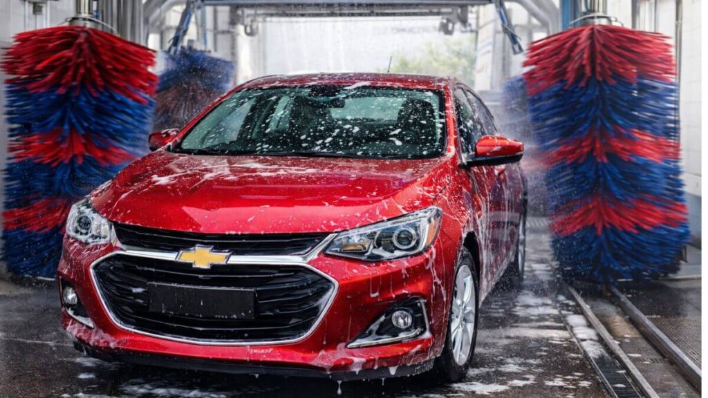 Chevrolet Onix vermelho sendo lavado em lava-jato automático profissional