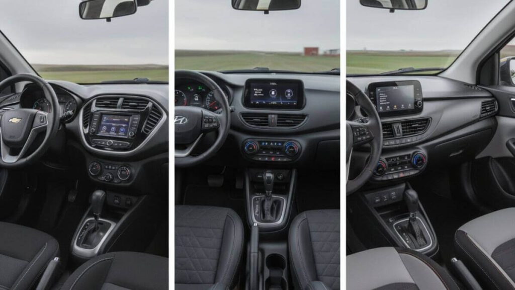 Montagem comparativa mostrando o design interno e acabamento de três carros: Chevrolet Onix, Hyundai HB20 e Fiat Argo. Foco nos painéis modernos, centrais multimídia, volantes e detalhes dos bancos de cada modelo.
