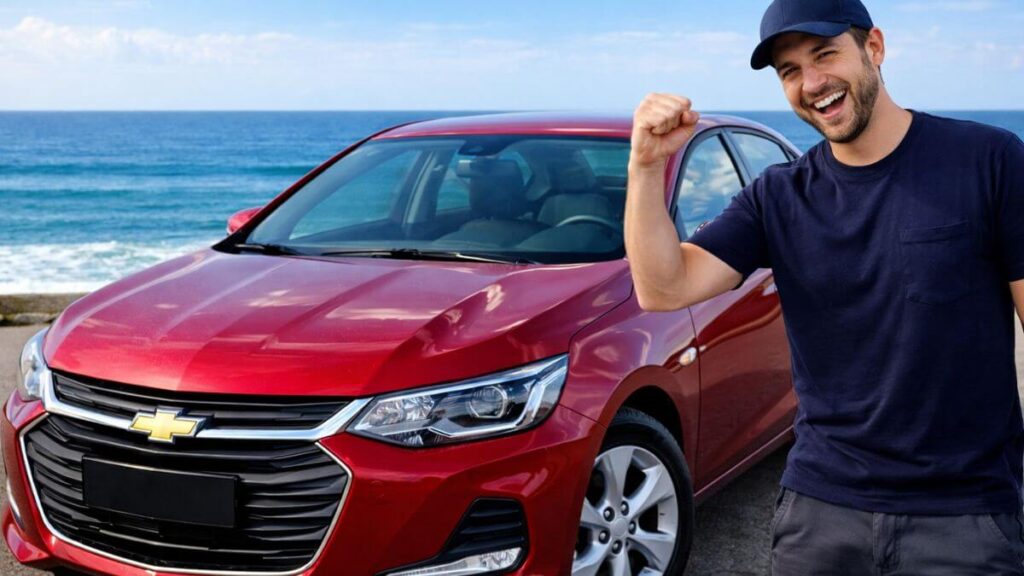 Homem sorridente ao lado de um Chevrolet Onix vermelho, recém-lavado, em ambiente limpo, com o carro brilhando e mostrando cuidado e proteção da pintura.