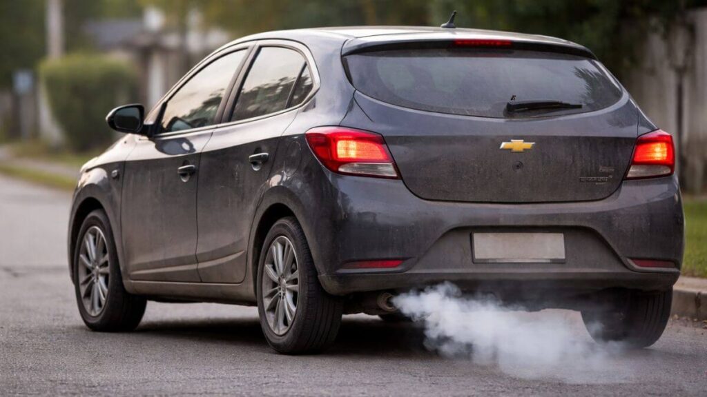 Chevrolet Onix com aparência de desgaste emitindo fumaça leve pelo escapamento indicando sinais de manutenção necessária