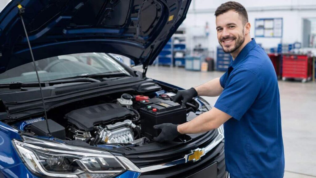 Troca de bateria do Chevrolet Onix em oficina mecânica Mecânico instalando bateria nova em um Chevrolet Onix azul em oficina mecânica