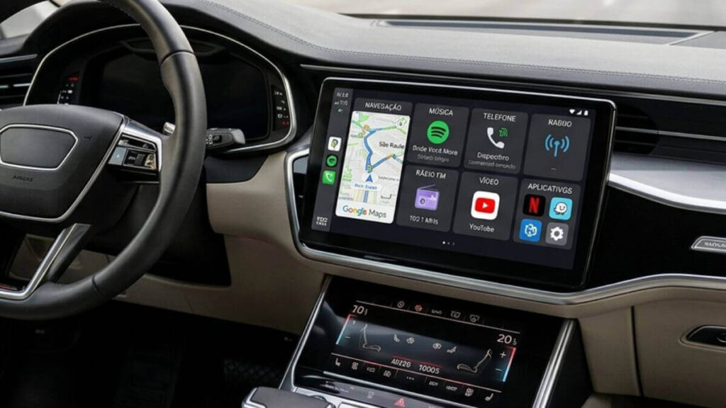 Central Multimídia Android Premium: Tecnologia Top de Linha no Seu Carro Foto do interior de um carro de luxo moderno, focado no painel e na central multimídia Android Premium top de linha. A tela touch exibe um menu com ícones coloridos para Google Maps, Spotify, Telefone e outros aplicativos. O volante de couro está à esquerda e a vista através do para-brisas mostra uma avenida arborizada com tráfego.