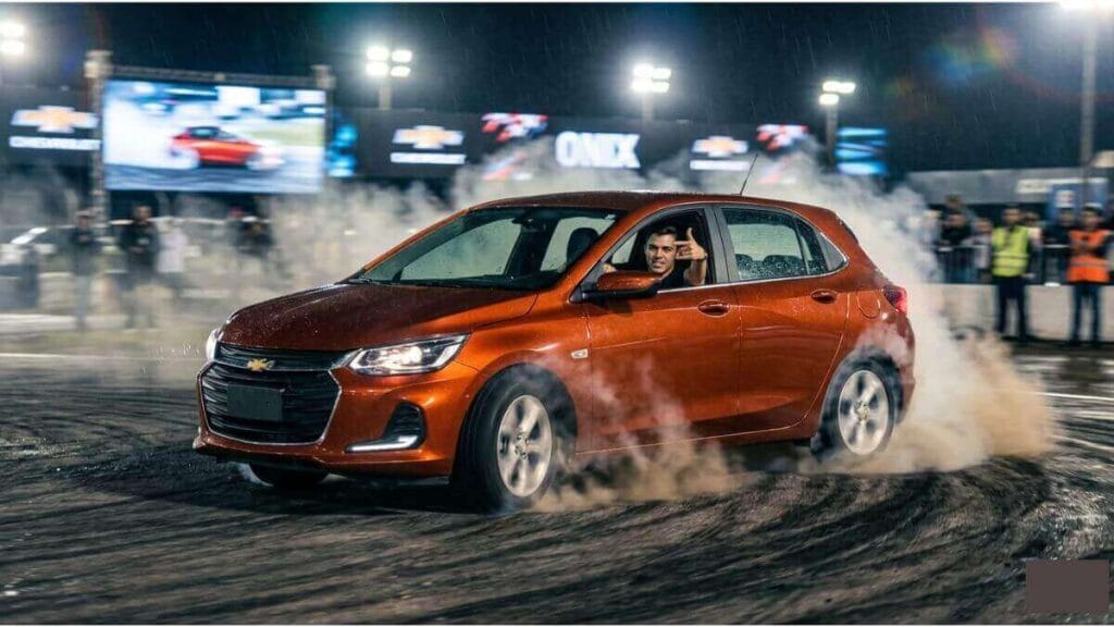 Chevrolet Onix realizando derrapagem com fumaça dos pneus em pista, demonstrando direção agressiva