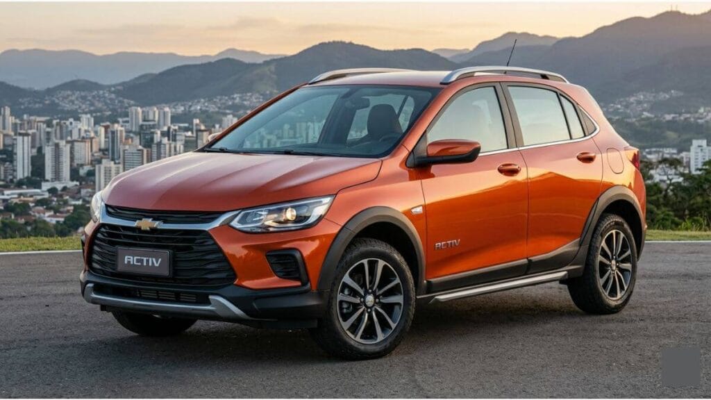 Chevrolet Onix Activ 2027 na cor laranja metálica, estacionado em um mirante com vista para uma cidade entre montanhas ao fundo. O hatch aventureiro exibe suspensão elevada, rack de teto cromado e molduras pretas nos para-lamas.