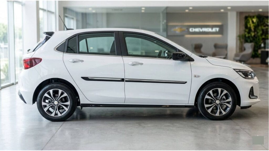 Vista lateral de um Chevrolet Onix branco estacionado dentro de uma concessionária Chevrolet moderna, mostrando o design das portas e rodas.