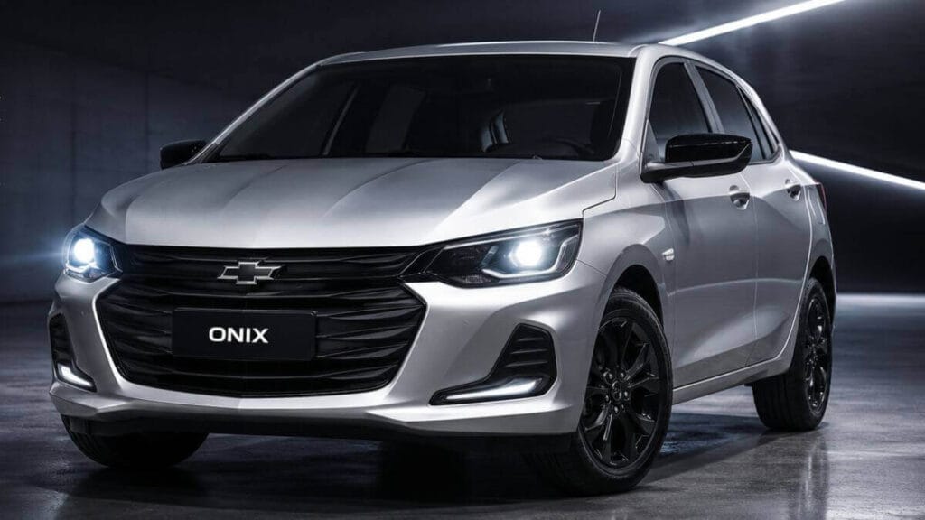 Chevrolet Onix prata com máscara negra e aplique de farol em destaque, mostrando visual moderno e esportivo com foco nos faróis acesos.
