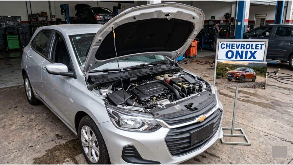 Motor do Chevrolet Onix aberto para manutenção preventiva de consumo Chevrolet Onix prata com o capô aberto em uma oficina mecânica, mostrando o motor exposto para manutenção preventiva.