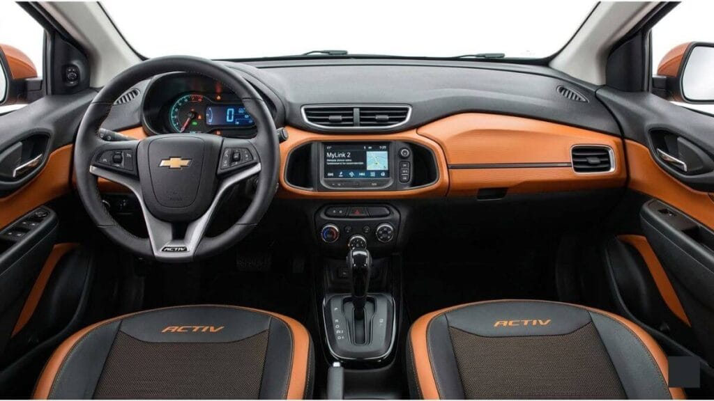 Público-alvo do Chevrolet Onix Activ Visão geral do interior bicolor em preto e laranja do Onix Activ, ideal para quem busca um hatch compacto diferenciado e com boa revenda.